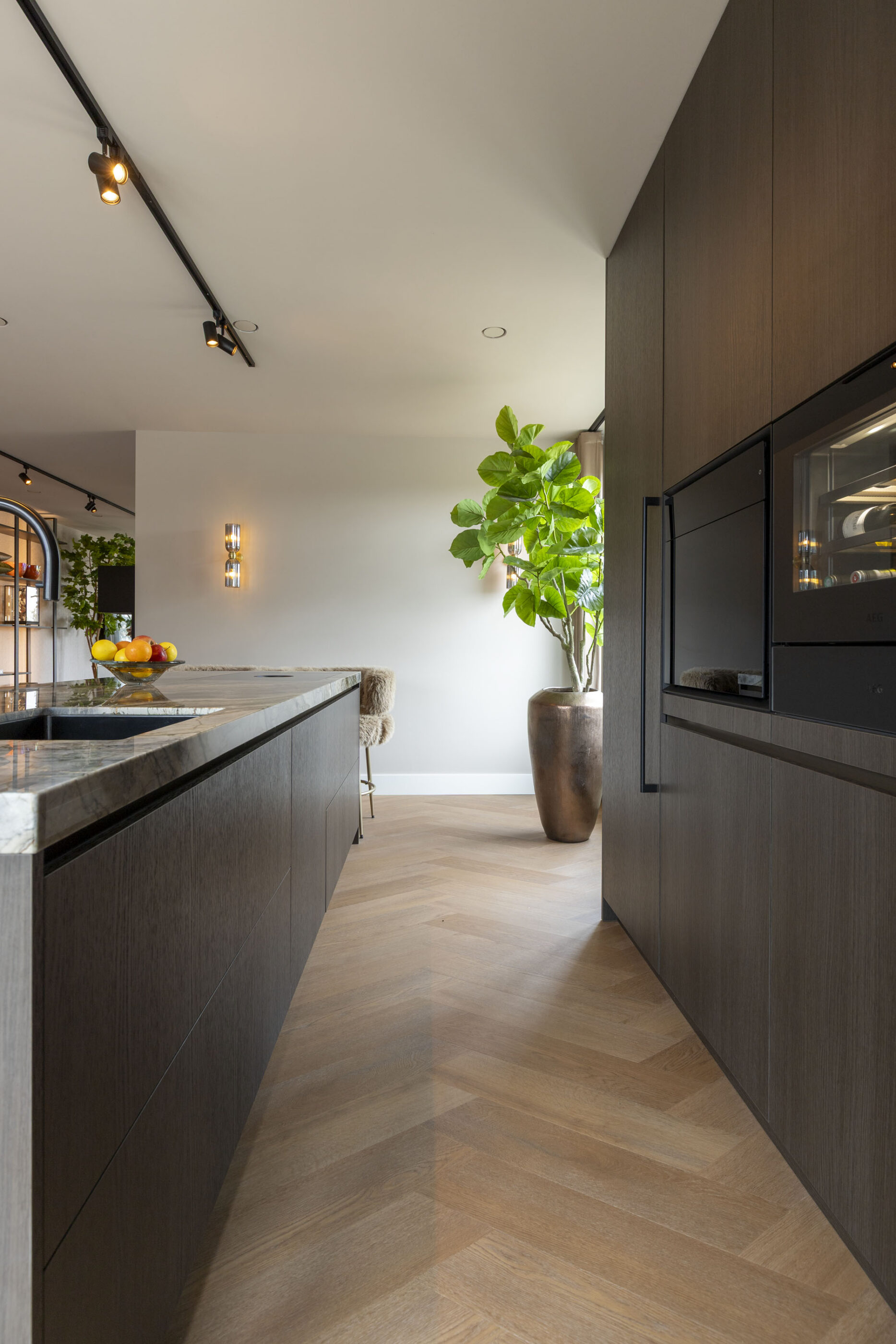 Moderne houtlook keuken met royaal kookeiland en een Montagne Blue keukenblad, ontworpen voor een luxe leefkeuken.