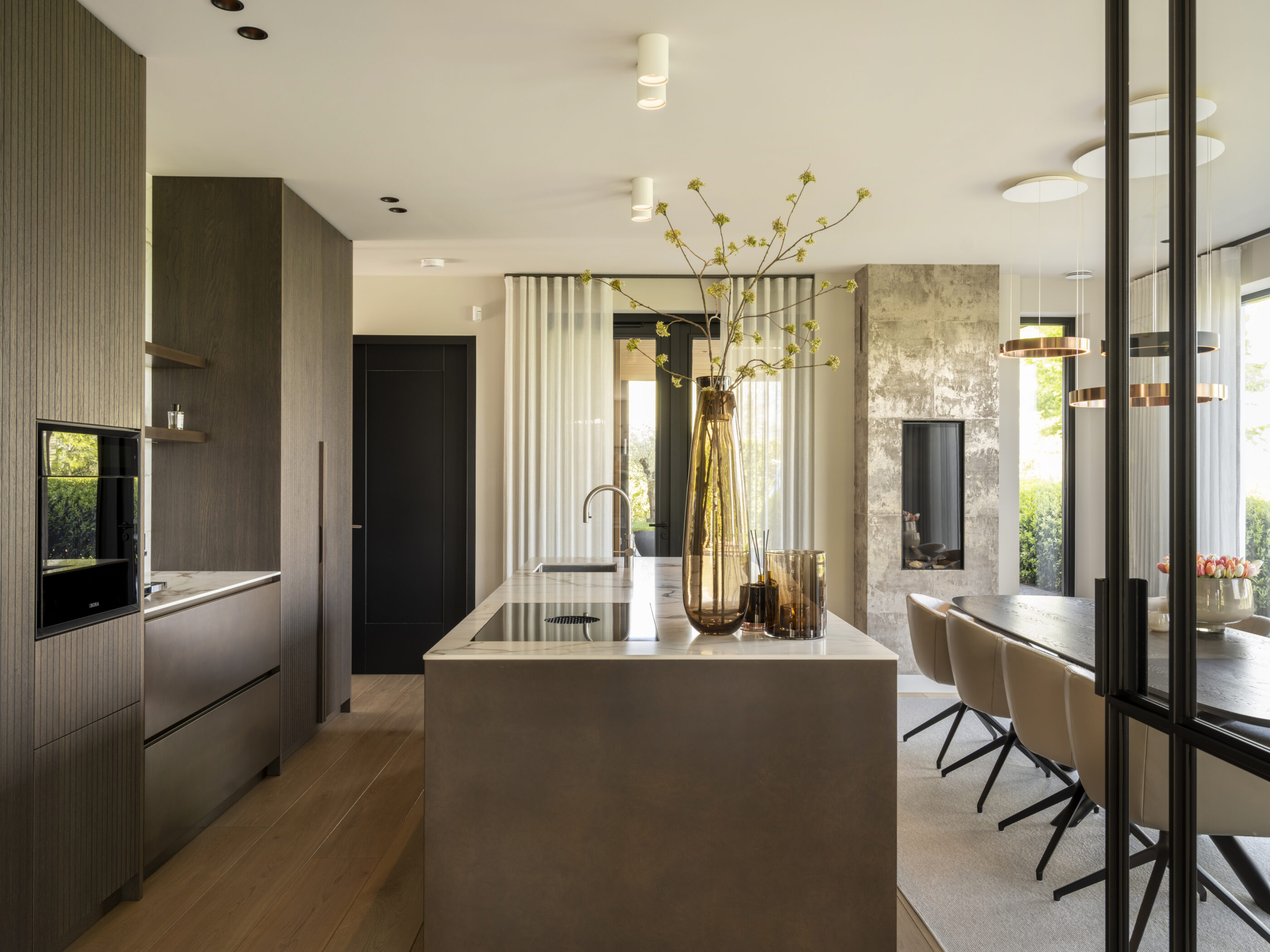 Maatwerk keuken met plafondhoge kastenwand, warm tabak-tinten en luxe afwerking door Rhijnart Keukens.