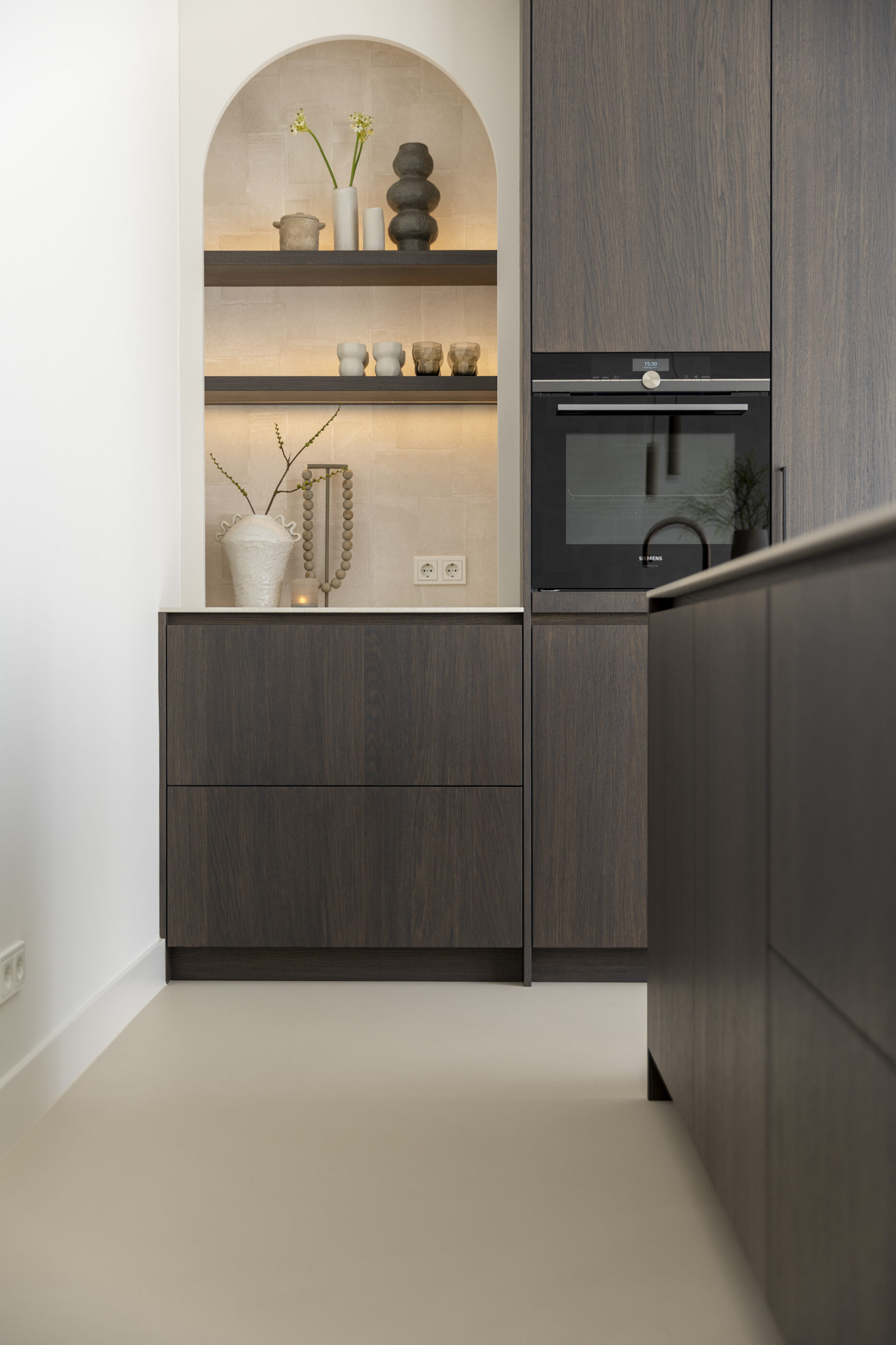 Architectonische nis in wandopstelling met ronde toogvorm, uitgevoerd in licht steenmateriaal als stijlvol keuken- en interieurelement.